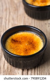 Creme Brûlée In A Black Ramekin, Wooden Table 