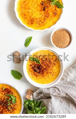 Creme brulee with caramel crust and mint in white ceramic dishes. Famous french dessert. Delicious desserts for cafe or restaurant. Top view.
