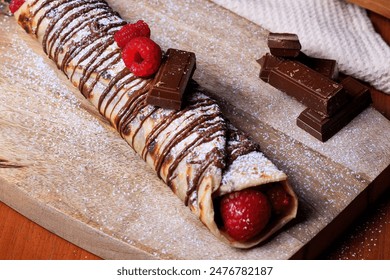A crepe roll with chocolate, icing, powdered sugar, and raspberries - Powered by Shutterstock