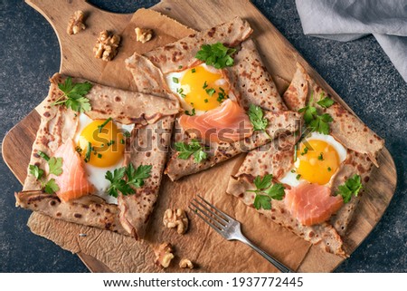 Crepes with eggs, salmon, spinach and nuts. Traditional dish galette sarrasin or buckwheat crepe, french brittany cuisine.