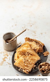 Crepes with honey or syrup and nuts Walnut on textured background close up with text space. Pancake day or Maslenitsa traditional food concept. Vertical orientation - Shutterstock ID 2258690875