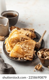 Crepes with honey or syrup and nuts Walnut on textured background close up with text space. Pancake day or Maslenitsa traditional food concept. Vertical orientation - Shutterstock ID 2258690879