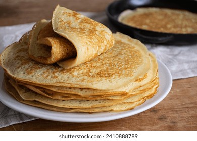 Crepes (Russian Blini) on wooden background, side view. Homemade thin fresh crepes for breakfast
