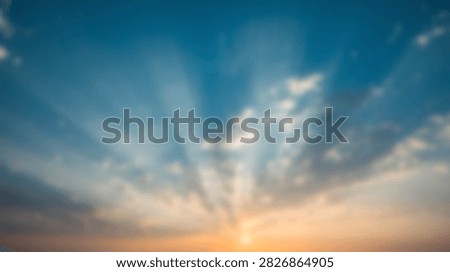 Crepuscular rays piercing through clouds in a blue and orange sky at sunset