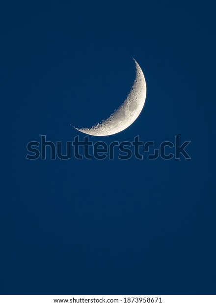 A crescent moon in the\
blue sky.