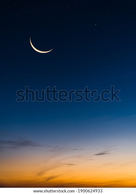 Crescent Moon on Twilight Sky in Evening Vertical\
with colorful sunlight after sundown,symbol Islamic Religion\
Ramadan, Dusk sky space background well for Arabic text present Eid\
al Adha, Eid al fitr.