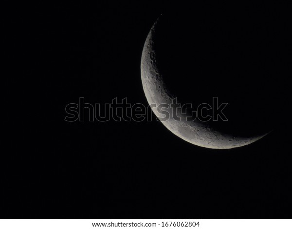 Crescent moon showing textures on the moon surface and\
craters. 