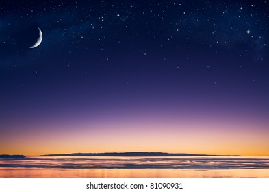 A crescent moon   stars over an island in the Pacific ocean just after sunset 