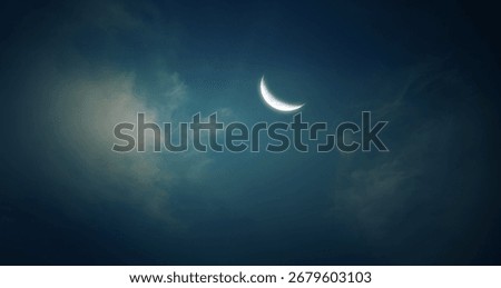 Crescent moon and thin clouds in the dark midnight sky. Mysterious night sky view.