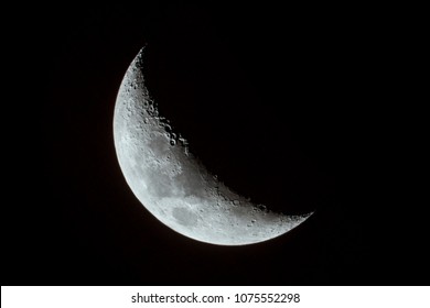 Crescent Moon with visible craters, mountains and lunar mare.