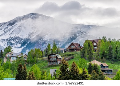 Crested Butte, USA Colorado town village in summer with clouds and foggy mist morning and houses on hillside with green trees - Powered by Shutterstock