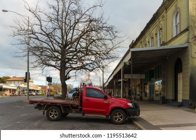 Creswick, AUSTRALIA - Aug 17 2018: Farmer Red Off Road Vehicle UTE With Kelpie Dogs On Platform Behind Driver Cabin, Iconic Australian Farming Scene In Front Of The Shop In Main Street Of The Town