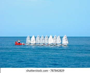 Crete, Greece - October 25, 2016: Training of children on dinghies. Trainer on red dinghy. Junior yachtsmen on sailboats in a row in the open sea.