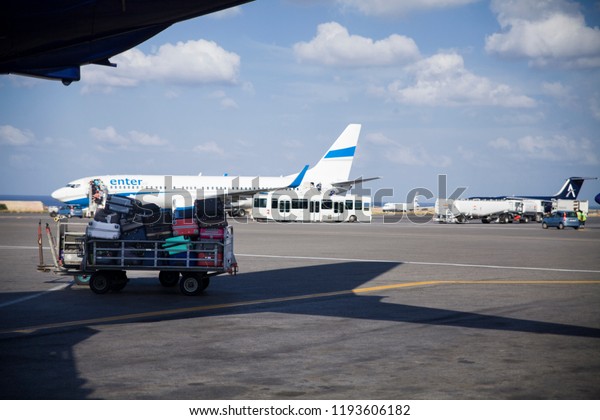 Crete / Greece - September 27,\
2018:Car and trailer with suitcases and luggage under the plane.\
.Morning at the airport. Airport on the island of Crete in\
Greece.