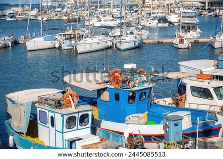 Crete island, destination Greece. Moored vessel with mast and fishing boat at Heraklion old Venetian harbor, calm sea water, blue sky background.