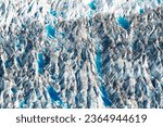 Crevasses in glacier surface nature pattern abstract texture aerial view with deep blue meltwater pools thawing from global warming climate change