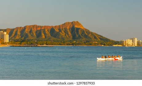 A Crew Of Boys Paddle An Outrigger Canoe At Waikiki Beach With Diamond Head In The Distance