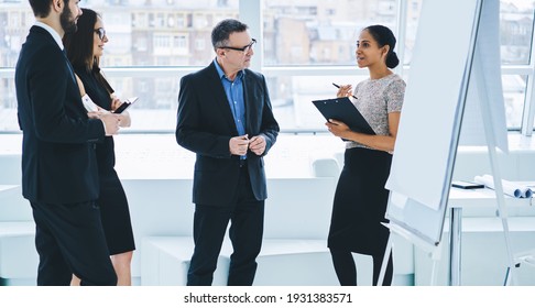 Crew Of Confident Male And Female Colleagues Discussing Ideas For Productive Work In Own Company,group Of Business People Talking About Entrepreneurship And Collaboration In Board Room With Flip Chart