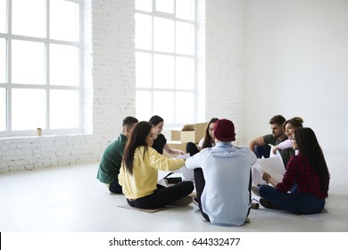 Crew Of Skilled Male And Female Colleagues Planning New Office Interior Sharing Ideas While Sitting In Circle On White Promotional Background, Students Talking To Each Other In Friendly Atmosphere