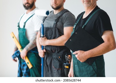 Crew of three professional builder wearing overalls standing in empty interior