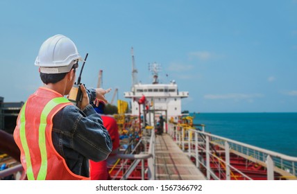 crew worker on tanker ship, Male worker at construction site with hand holding walkie-talkie operation work by pointing hand wearing safety helmet hard hat  - Shutterstock ID 1567366792