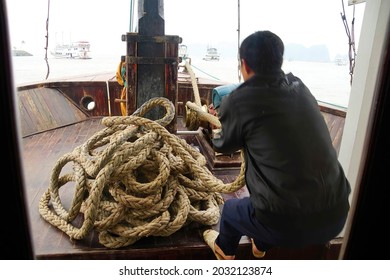 Crewman Hauling In The Anchor On Cruise Ship Junk,  Halong Bay, Vietnam