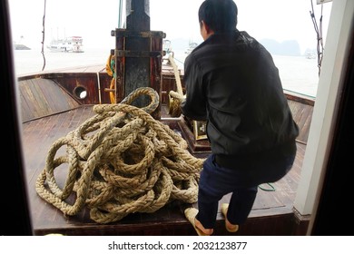 Crewman Hauling In The Anchor On Cruise Ship Junk,  Halong Bay, Vietnam