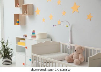 Crib With Toy Bear And Mobile In Stylish Baby Room Interior