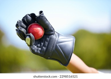 Cricket, ball and hand with a wicket keeper making a catch during a sports game outdoor on a pitch. Fitness, glove and caught with a sport player playing a competitive match outside during summer
