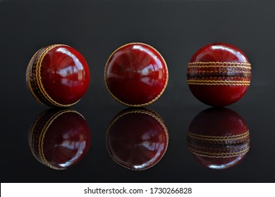 Cricket ball leather hard circle stitch close-up reflection on dark background.