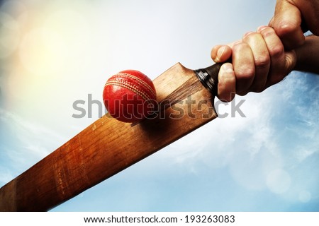 Cricket batsman hitting a ball shot from below against a blue sky