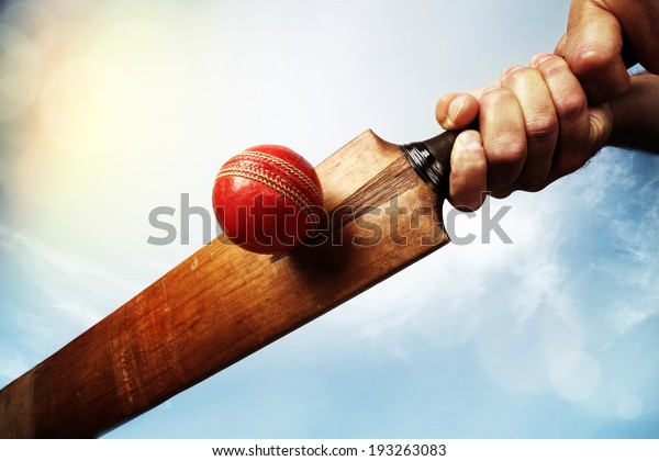 Cricket batsman hitting a ball shot from below
against a blue sky