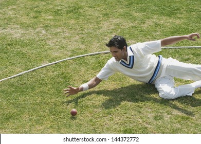 Cricket fielder diving to stop a ball near boundary line - Powered by Shutterstock