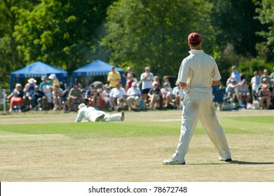 Cricket On A Picturesque English Village Green On A Bright Summers Day