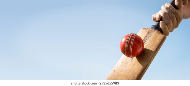 Cricket player batsman hitting a ball with a bat shot from below against a blue sky background - Powered by Shutterstock