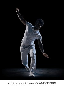 Cricket player dynamic pose with raised arm and ball on dark studio background. Concept of athlete branding, social media sports content, commercial for activewear label and online promotion.