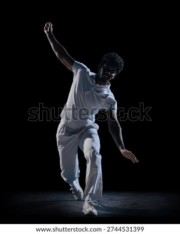 Cricket player dynamic pose with raised arm and ball on dark studio background. Concept of athlete branding, social media sports content, commercial for activewear label and online promotion.