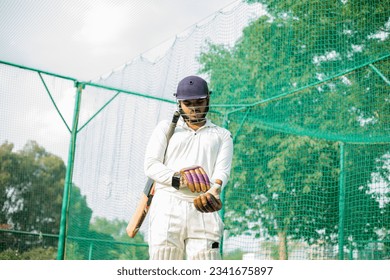 Cricket Player wearing gloves to do practice in cricket nets.  - Powered by Shutterstock