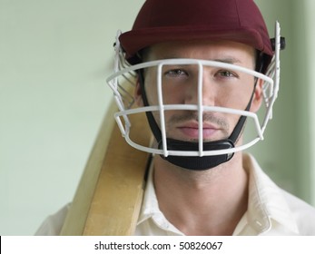 Cricket player wearing helmet and holding bat, close-up, portrait
