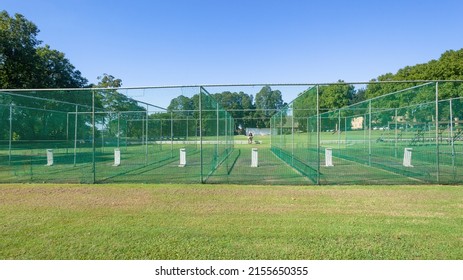 Cricket practice with six batting wickets grass pitch nets close-up outdoor.
