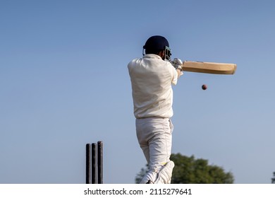 A cricketer playing cricket on the pitch in white dress for test matches. Sportsperson hitting a shot on the cricket ball. - Shutterstock ID 2115279641