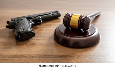 Crime, Gun Carry And Use Punishment Concept. Judge Gavel And Handgun On Lawyer Office Desk. Wooden Courthouse Table, Close Up View