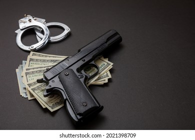 Crime And Law Concept. Pistol Handgun 9 Mm, Hand Cuffs And American Dollar Banknotes On Black Background. Criminal Money And Punishment, Copy Space, Template