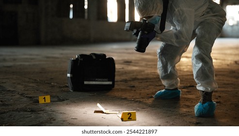 Crime, person and photography at scene for evidence, documentation and spotlight in abandoned warehouse. Forensic specialist, PPE or camera in building for legal service, clue inspection or pathology - Powered by Shutterstock