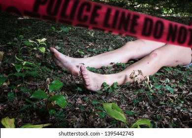 Crime Scene With A Dead Body And Red Cordon Tape, Naked Female Legs Lying In Grass And Leaves In Forest With Red 