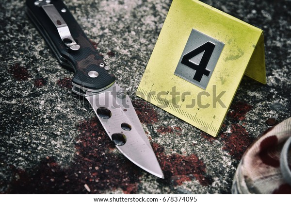 Crime scene investigation, Bloody knife and\
victim\'s shoes with criminal markers on ground, Homicide evidence.\
(Selective Focus)