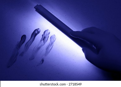 Crime Scene Investigation Technician Hand Holding UV Black Light Wand To Reveal Bloody Finger Print Smear In A Crime Scene (fictitious Representation)