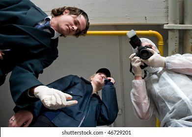 Crime Scene Investigations Team Hovering Over My Dead Body. A Police Inspector, Wearing Rubber Gloves, A Policewoman Using Her Radio, And Forensic Expert Taking Pictures As Evidence