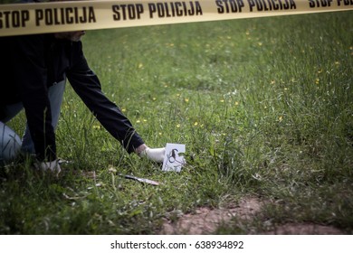 The Crime Scene, Murder, Investigation, Bloody Knife On The Grass, An Investigation Is Underway, Expert Witness With Gloves Puts Labels On The Crime Scene