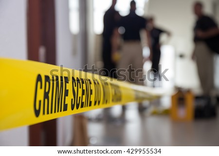 crime scene tape in building with blurred forensic team background